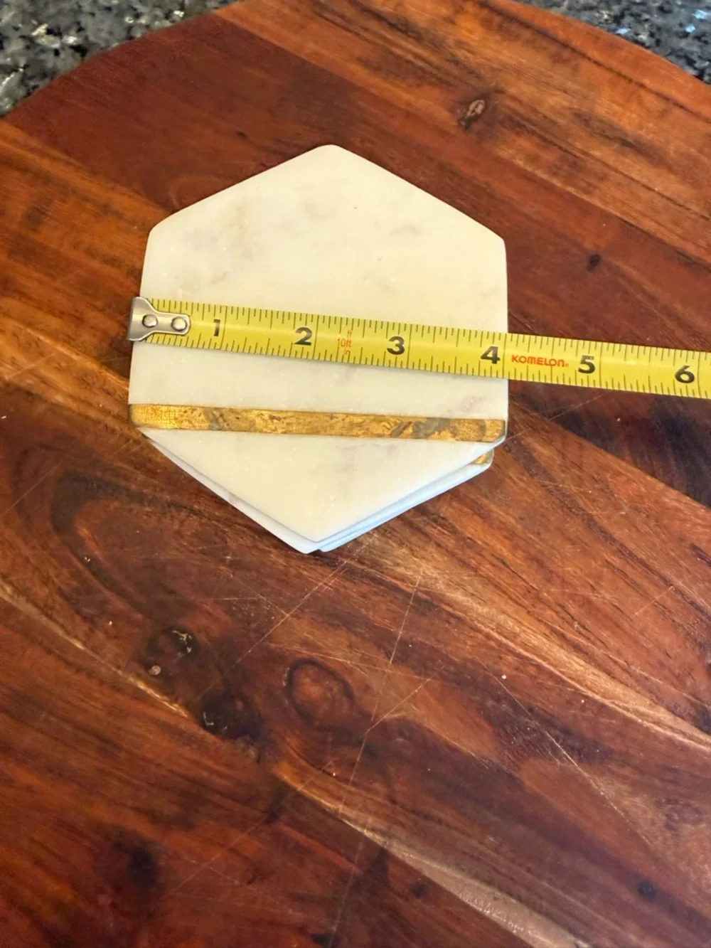 Hexagonal white marble coasters featuring a brass inlay design